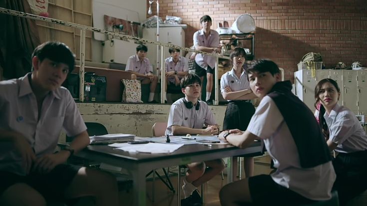 Para pemeran The Gifted duduk dan berdiri di ruang kelas
             yang remang dengan dinding bata merah, seragam putih abu-abu
             khas sekolah Thailand, ekspresi serius dan penuh ketegangan